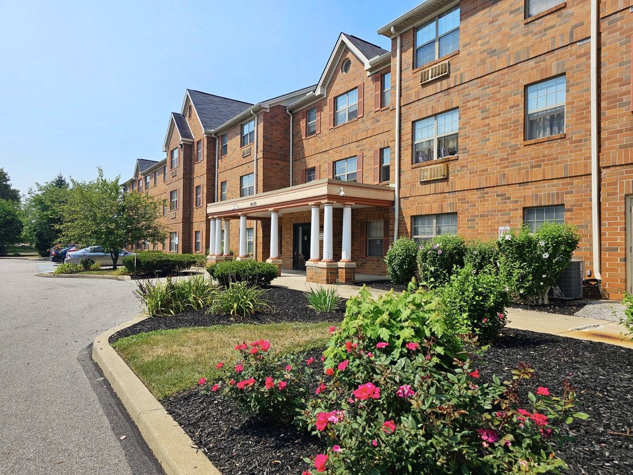 Ascension Village brick apartment building with flower beds and mature landscaping.