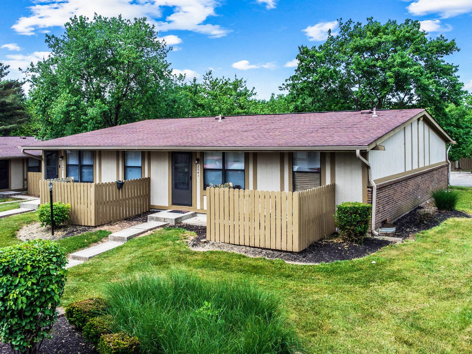 Woodgate Apartments exterior with renovated siding, fencing and landscaped grounds.