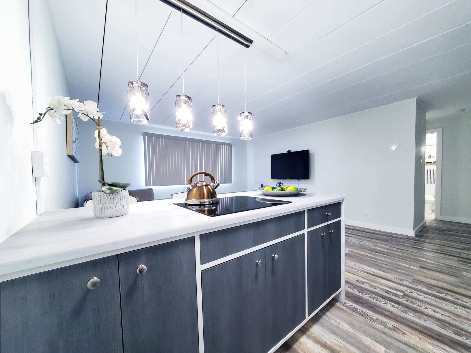 Completed apartment kitchen with dark flat-panel cabinetry, quartz counters and pendant lighting.
