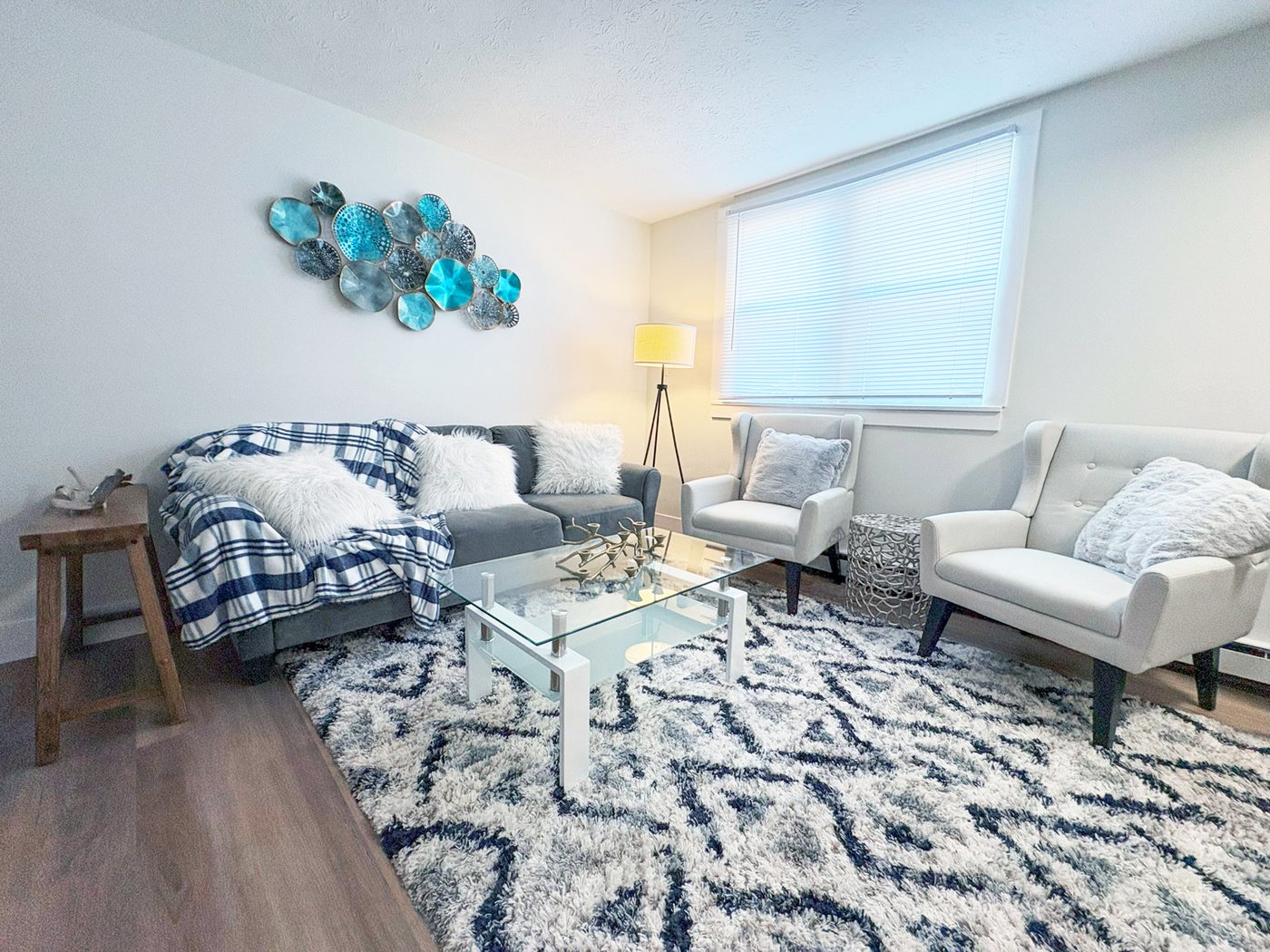 A renovated and staged apartment living room with wide-plank flooring, fresh paint and new lighting.