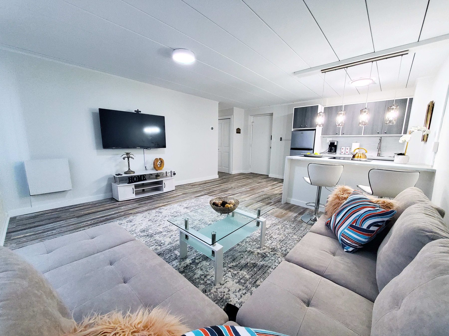 A fully renovated open-plan apartment living area and kitchen with wide-plank flooring.